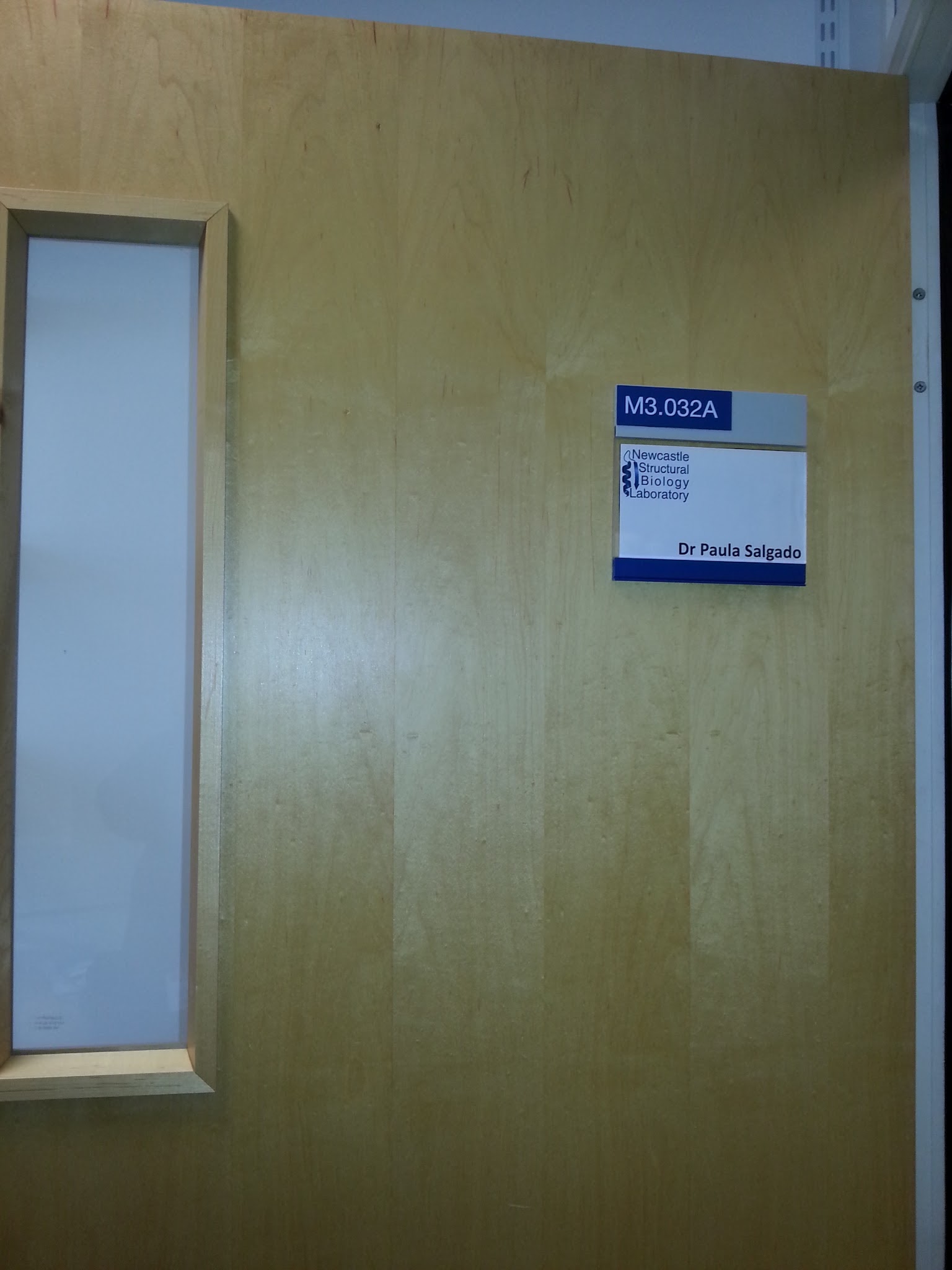 A light wooden office door with a nameplate reading M3.032A, Newcastle Structural Biology Laboratory, Dr Paula Salgado.